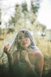 Portrait of woman wearing netting against trees