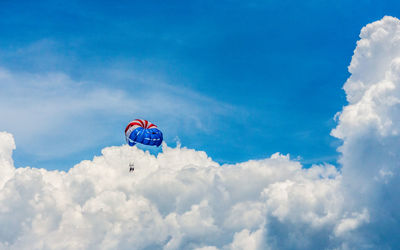 Low angle view of parachute flying against cloudy sky