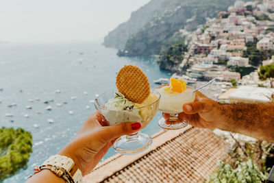 Midsection of person holding ice cream against sea