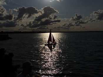Silhouette people on sea against sky