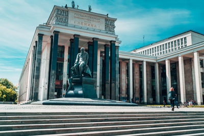 Statue in city against sky