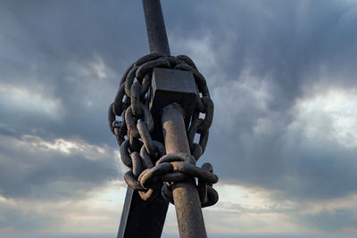 Low angle view of  metal chain against sky