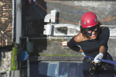 A woman dressed as a hero with a protective helmet holding the rappel rope.