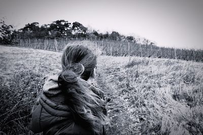 Rear view of woman by plants against clear sky