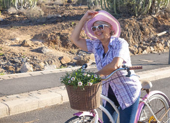 Smiling senior woman with bicycle on road