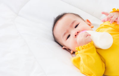 High angle portrait of baby girl lying on bed