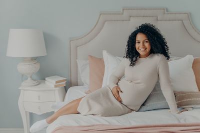 Portrait of woman sitting on bed at home