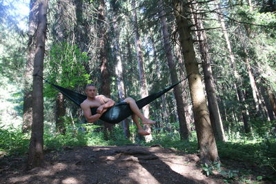 Young woman lying down on tree trunk in forest