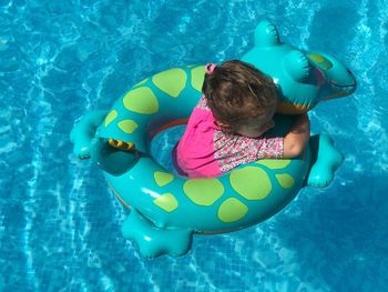 High angle view of girl with inflatable raft in swimming pool on sunny day