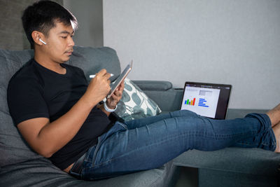 Midsection of man using mobile phone while sitting on sofa