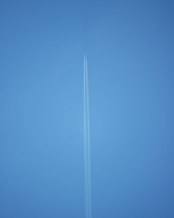 Low angle view of airplane flying against clear blue sky