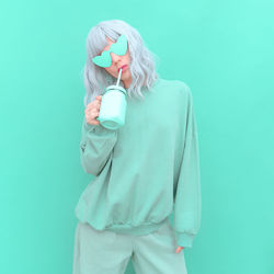 Portrait of woman drinking juice against colored background