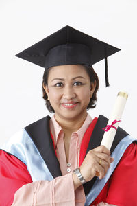 Portrait of woman in graduation gown against white background