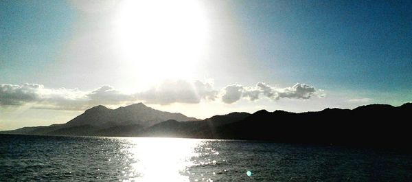 Sun shining through clouds over mountains