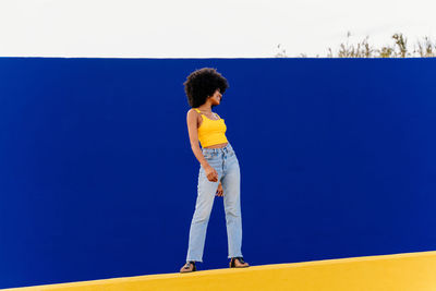 Rear view of woman standing against blue background