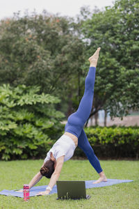 Low section of woman with arms raised against trees