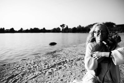 Portrait of woman standing by lake against sky