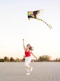 Full length of woman flying kite against clear sky