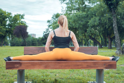 Rear view of doing splits on bench at park