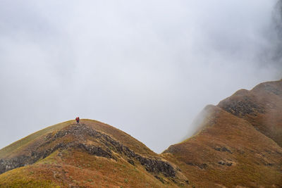 Scenic view of a hiker on mountain ridge in heavy fog 