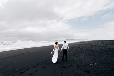 Rear view of couple walking on footpath against sky