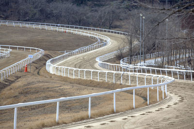 Dirt road by white railing