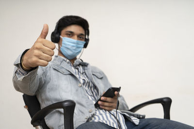 Full length portrait of young man sitting on mobile phone