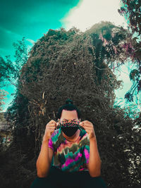 Portrait of woman wearing sunglasses standing against trees