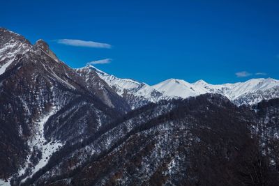 Scenic view of snowcapped mountains against blue sky