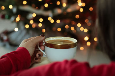 Woman holding coffee cup in front of chistmas tree 