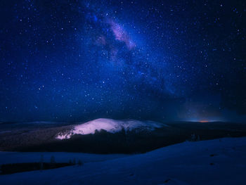 Scenic view of snowcapped mountains against sky at night