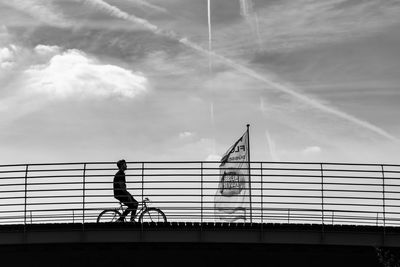 Silhouette man walking on bridge against sky