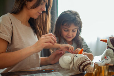Mother and daughter making christmas decoration while sitting at home