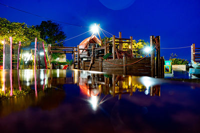 Illuminated bridge over river against sky at night