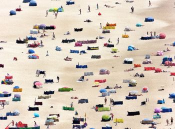 High angle view of people and parasols at beach during sunny day