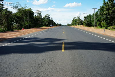 Road by trees against sky