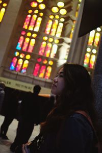 Full length portrait of woman standing in illuminated room