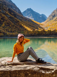 Portrait of woman sitting on rock by lake