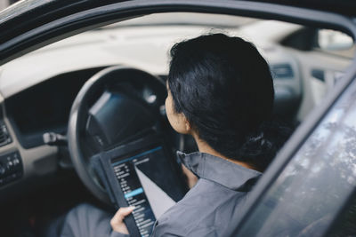 Female mechanic using digital tablet while sitting in car