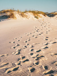 Footprints on sand at beach against sky