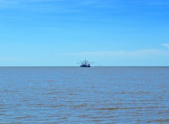 Boat sailing in sea against blue sky