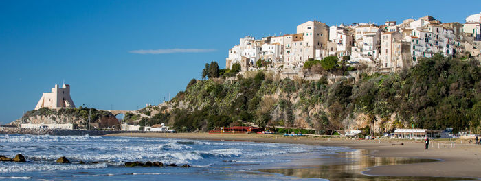 Buildings by sea against sky in city