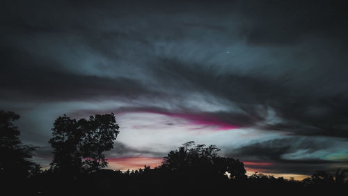 Silhouette of trees against cloudy sky