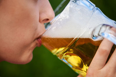 Close-up of hand holding glass of beer bottle