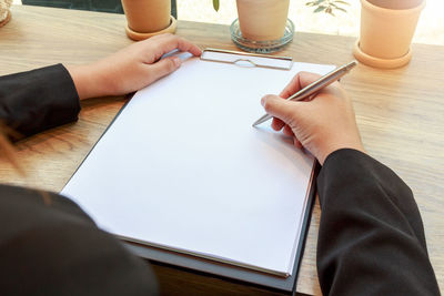 Low section of man holding paper on table