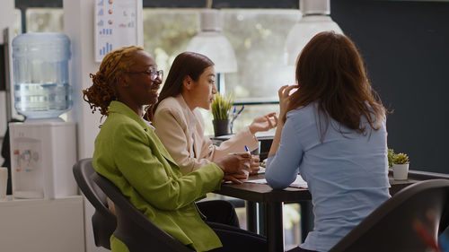 Side view of female friends working at home