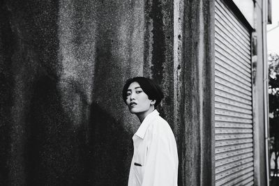 Portrait of young woman standing against wall