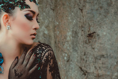 Portrait of young woman looking away against wall
