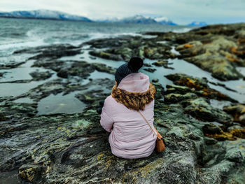 Rear view of woman sitting on rock