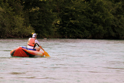 Man sitting in boat against sky